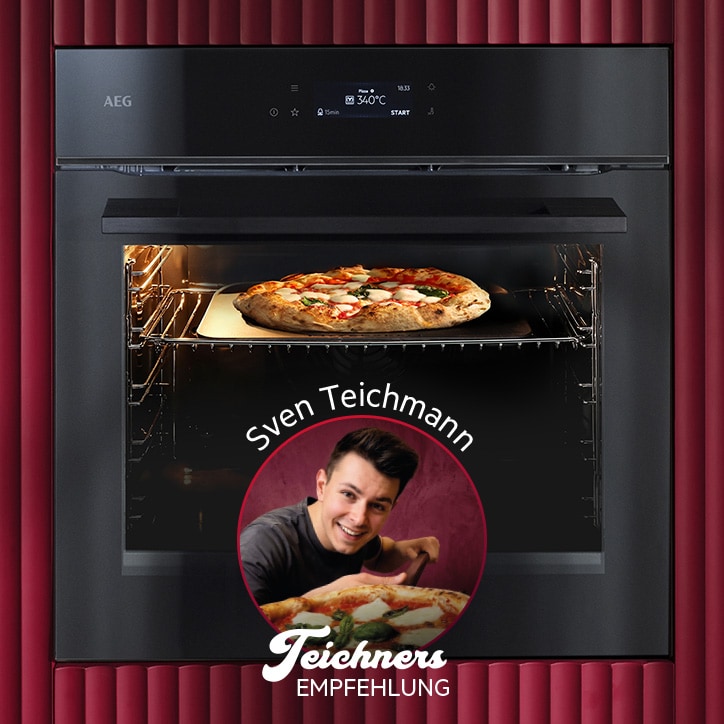 Ein schwarzer AEG Einbaubackofen mit geöffnetem Garraum, in dem eine Pizza auf einem Pizzastein backt. Über dem Backofen ist ein digitales Display sichtbar. Auf der Backofentür befindet sich ein rundes Teaser‑Motiv mit einer Person, einer Pizza und dem Text „Sven Teichmann – Teichners Empfehlung“. Der Hintergrund ist in dunklem Rot gestaltet.