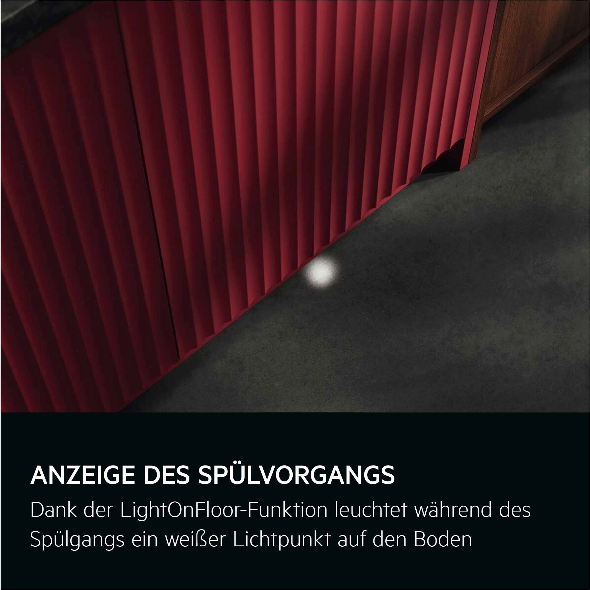 Weißer Lichtpunkt auf dunklem Küchenboden zeigt aktiven Spülvorgang durch AEG LightOnFloor-Funktion.