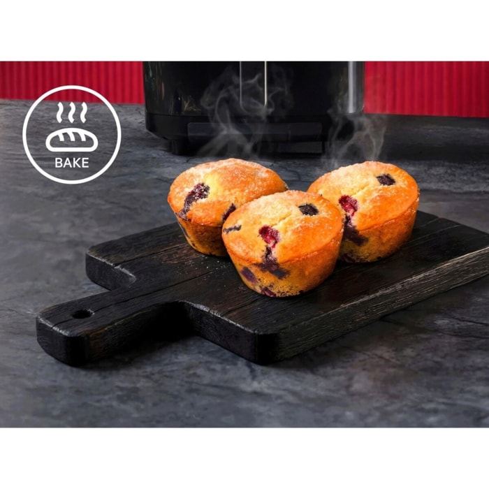 Drei dampfende Muffins auf Holzbrett vor schwarzem Gerät, links ein Bake‑Symbol mit Brot‑Icon