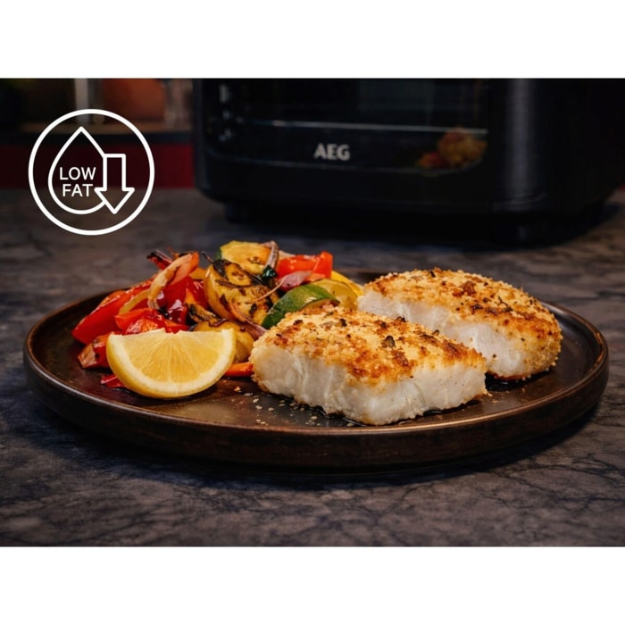 Teller mit zwei gebackenen Fischfilets, gebratenem Gemüse und Zitronenscheibe vor einem Airfryer; „Low Fat“-Symbol links