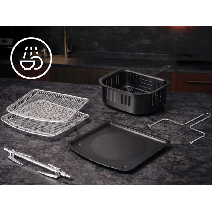 Airfryer‑Zubehörteile liegen auf einer Küchenarbeitsfläche; links oben ein Symbol für spülmaschinenfeste Reinigung