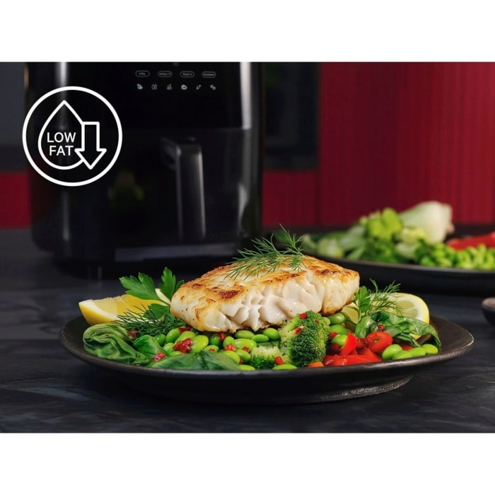Gebratenes Fischfilet auf Gemüseplatte; links oben Low‑Fat‑Symbol. Im Hintergrund steht ein Airfryer