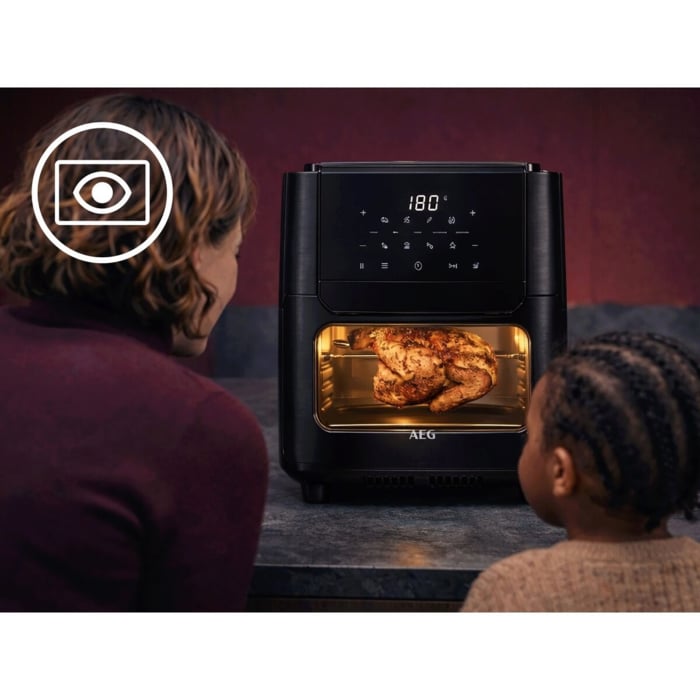 Zwei Personen betrachten ein im Airfryer garendes Hähnchen; links oben Symbol mit Auge und Rahmen.