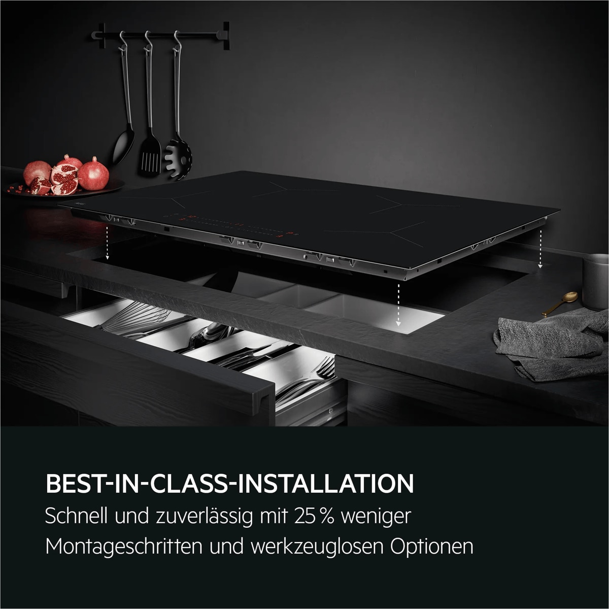 Ein Induktionskochfeld wird über einer Arbeitsplatte installiert; darunter geöffnete Schubladen mit Küchenutensilien.