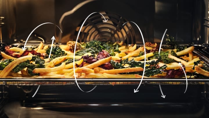 Pommes frites und Gemüse werden in einem Backofen zubereitet.