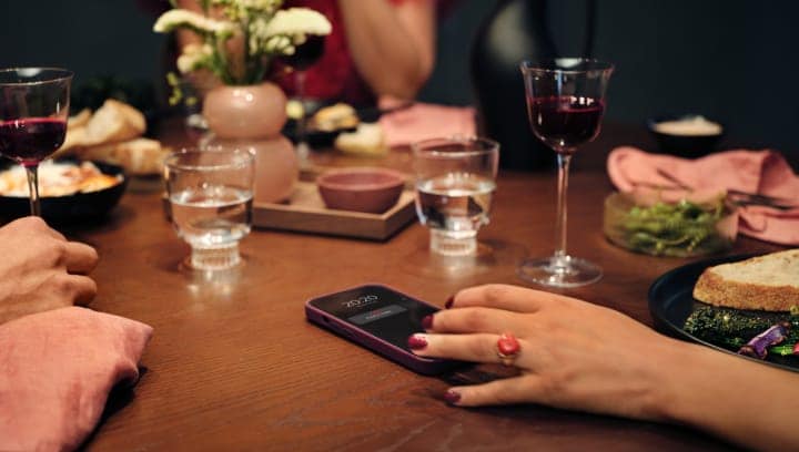 Personen sitzen an einem Tisch mit Essen und Getränken.