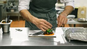 Ein Koch, der einen Teller mit einer perfekt präsentiertem Gourmet-Speise anrichtet