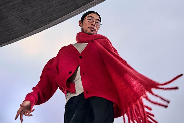ann mit rotem Wollschal und Cardigan aus Strickstoff in dynamischer Pose &ndash; Pflege hochwertiger Textilien mit AEG