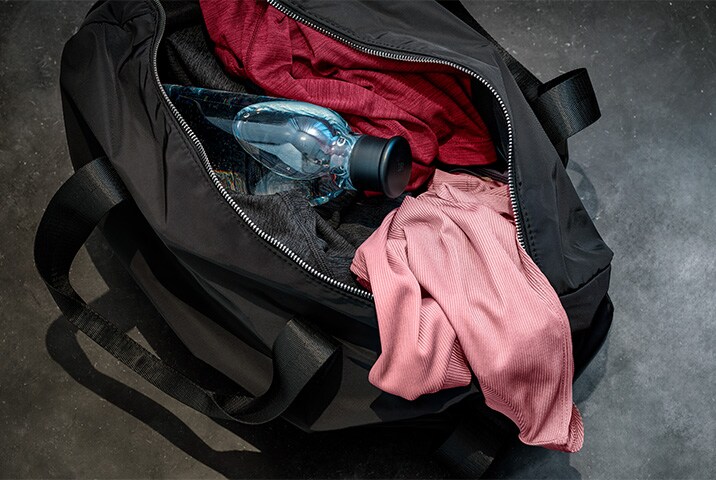 Schwarze Tasche mit Sportkleidung und einer Wasserflasche