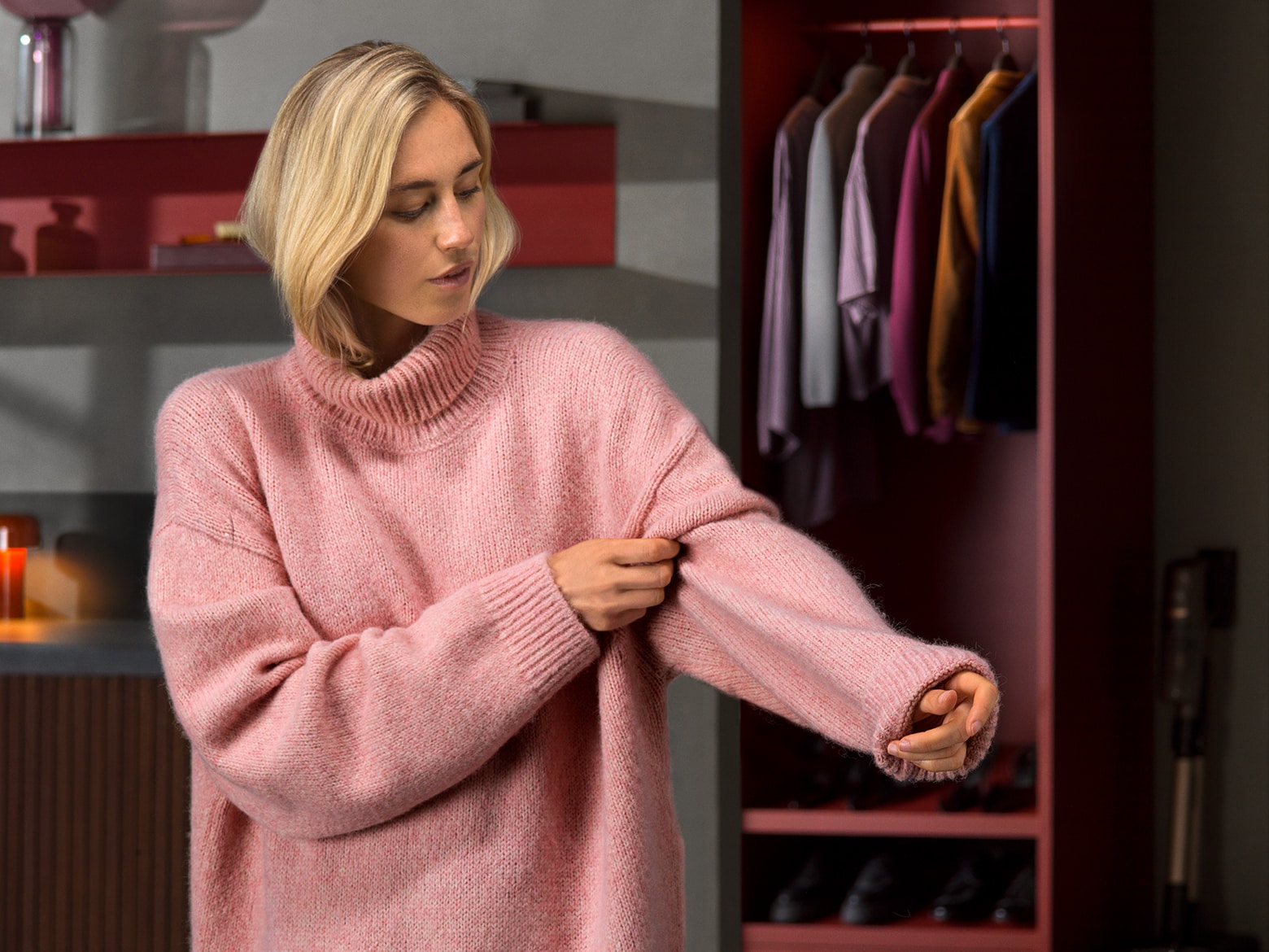 Blonde Frau in einem rosafarbenen Wollpullover mit Rollkragen