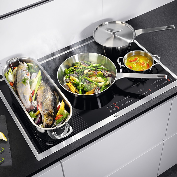 Ein AEG Induktionskochfeld wird zum Kochen verschiedener Speisen in Pfannen verwendet