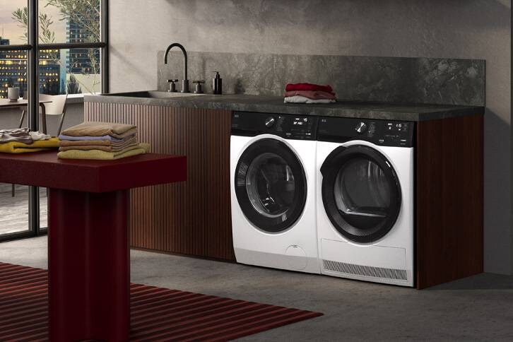 Eine Waschmaschine und ein Wäschetrockner stehen nebeneinander in einer Küchenzeile