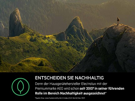 Person auf Berggipfel in grüner Landschaft bei Sonnenuntergang.
